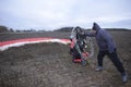 Paramotoring. Instructor starting the engine of paramotor by turning propeller, paramotorist kneeling to help him