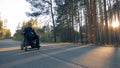 Paraplegic man is moving along the road on his powered wheelchair in the forest