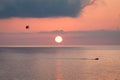 Parasailing behind a boat at sunset over the sea. Royalty Free Stock Photo