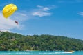 Parasailing is a popular water sport in Patong Beach, Thailand. People flying on colorful parachute towed by speed boat with a cle