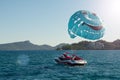 Parasailing, a red and white boat pulls a blue parachute with a smiley face