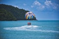 Parasailing on the waves of the azure Andaman sea under the blue sky near the shores of the sandy beautiful exotic and stunning Royalty Free Stock Photo