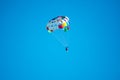 Parasailor on multi-colored parachute flying in blue clear sky, sunny weather, inspirational, summer, vacation