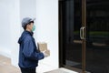 Parcel delivery concept the postman in white rubber gloves and light weight dark blue coat waiting to hand small parcels to his Royalty Free Stock Photo