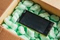Parcel of online shop, phone in a cardboard box on green styrofoam Royalty Free Stock Photo