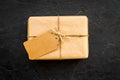 Parcel packaging box wrapped with craft paper with empty label mockup on black background top view copy space Royalty Free Stock Photo