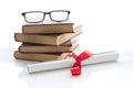 A parchment diploma scroll, rolled up with red ribbon beside a stack of books on white background.