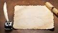 Parchment, quill and inkwell on a wooden table seen from above.