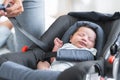 Parent is adjusting fastening safety belt to less than one month old newborn baby girl sleeping in the modern car seat. Selective Royalty Free Stock Photo