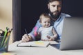 Parent with child studying remotely at homebased laptop. Distant education for people with babies.Man and toddler sitting at table Royalty Free Stock Photo