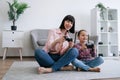 Parent and daughter playing video game with joypads on floor