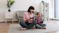 Parent and daughter playing video game with joypads on floor