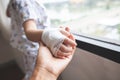 Parent hand holding sick son hand who have IV solution bandaged with love and care  while he looking outside through the window Royalty Free Stock Photo