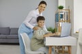 Happy parent or school teacher helping student boy while he uses laptop computer Royalty Free Stock Photo