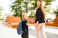 Mom leads her daughter to school. Return to school. Woman and girl with backpack behind the back. Beginning of lessons Royalty Free Stock Photo