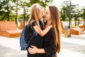 Mom leads her daughter to school. Return to school. Woman and girl with backpack behind the back. Beginning of lessons Royalty Free Stock Photo