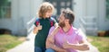 Parent and pupil of primary school with thumbs up sign. Teacher in t-shirt and cute schoolboy with backpack near school Royalty Free Stock Photo