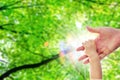 A one year old baby girl is grabbing her parent's hand, with a background of green trees and blur sun light