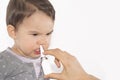 Parent's hand of a sick little girl applies a nasal spray