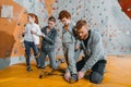 Parents securing their children in harnesses for climbing a wall with grips