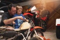 Parent, son and fixing with bike in garage at home for teamwork, support and repair with tools. Family, father and child