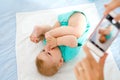 Parent taking photo of a baby with smartphone. Adorable newborn child taking foot in mouth Royalty Free Stock Photo