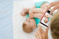 Parent taking photo of a baby with smartphone. Adorable newborn child taking foot in mouth Royalty Free Stock Photo