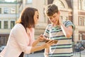 Parent and teenager, relationship. Mother shows her son something in mobile phone, boy is embarrassed, smiling, holding his hands Royalty Free Stock Photo
