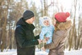 Parenthood, fashion, season and people concept - happy family with baby in winter clothes outdoors