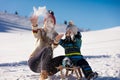 Parenthood, fashion, season and people concept - happy family with child on sled walking in winter outdoors