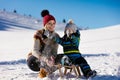 Parenthood, fashion, season and people concept - happy family with child on sled walking in winter outdoors Royalty Free Stock Photo