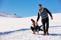 Parenthood, fashion, season and people concept - happy family with child on sled walking in winter outdoors