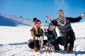 Parenthood, fashion, season and people concept - happy family with child on sled walking in winter outdoors Royalty Free Stock Photo