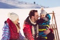 Parenthood, fashion, season and people concept - happy family with child on sled walking in winter outdoors Royalty Free Stock Photo