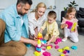 parents with adorable little children playing with colorful blocks at home