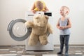 Parents bought a new washing machine. The children try to turn it on and wash the soft toys. Happy boys are playing at home