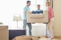 Parents carrying son on armchair in new house