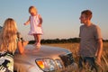 Parents and child on car cowl on wheaten field Royalty Free Stock Photo