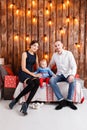 Parents and child having fun in loft-style room, wooden rustic background with a garland of bulbs. Loving family Merry Royalty Free Stock Photo