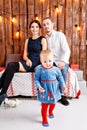 Parents and child having fun in loft-style room, wooden rustic background with a garland of bulbs. Loving family Merry Royalty Free Stock Photo