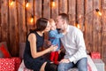 Parents and child having fun in loft-style room, wooden rustic background with a garland of bulbs. Loving family Merry Royalty Free Stock Photo