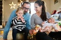 Parents with children at Christmas tree blowing party whistle