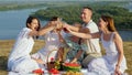 Parents with children clink glasses of soft drinks at picnic