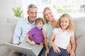 Parents and children with laptop sitting on sofa Royalty Free Stock Photo