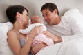 Parents Cuddling Newborn Baby In Bed Royalty Free Stock Photo