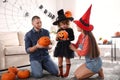 Parents and cute little girl with pumpkin candy bucket at Halloween party Royalty Free Stock Photo