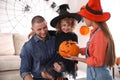 Parents and cute little girl with pumpkin having Halloween party at home