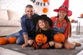 Parents and cute little girl with pumpkin having Halloween party at home Royalty Free Stock Photo