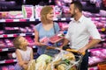 Parents with daughter choosing meat in refrigerated section in h Royalty Free Stock Photo