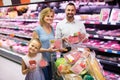 parents with daughter choosing meat in refrigerated section in hypermarket Royalty Free Stock Photo